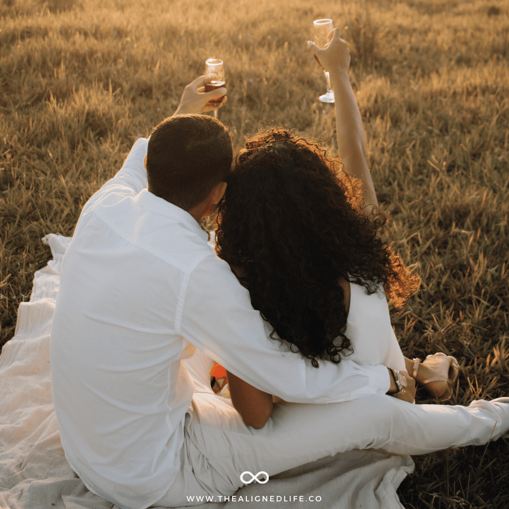 couple in a field toasting each other with wine | How To Manifest The Love You Deserve in 2025 | The Aligned Life Manifestation Blog