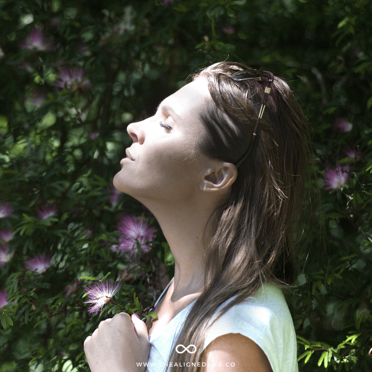 brunette woman with a flower | Signs Your Manifestation Is On Its Way | The Aligned Life Manifestation Blog