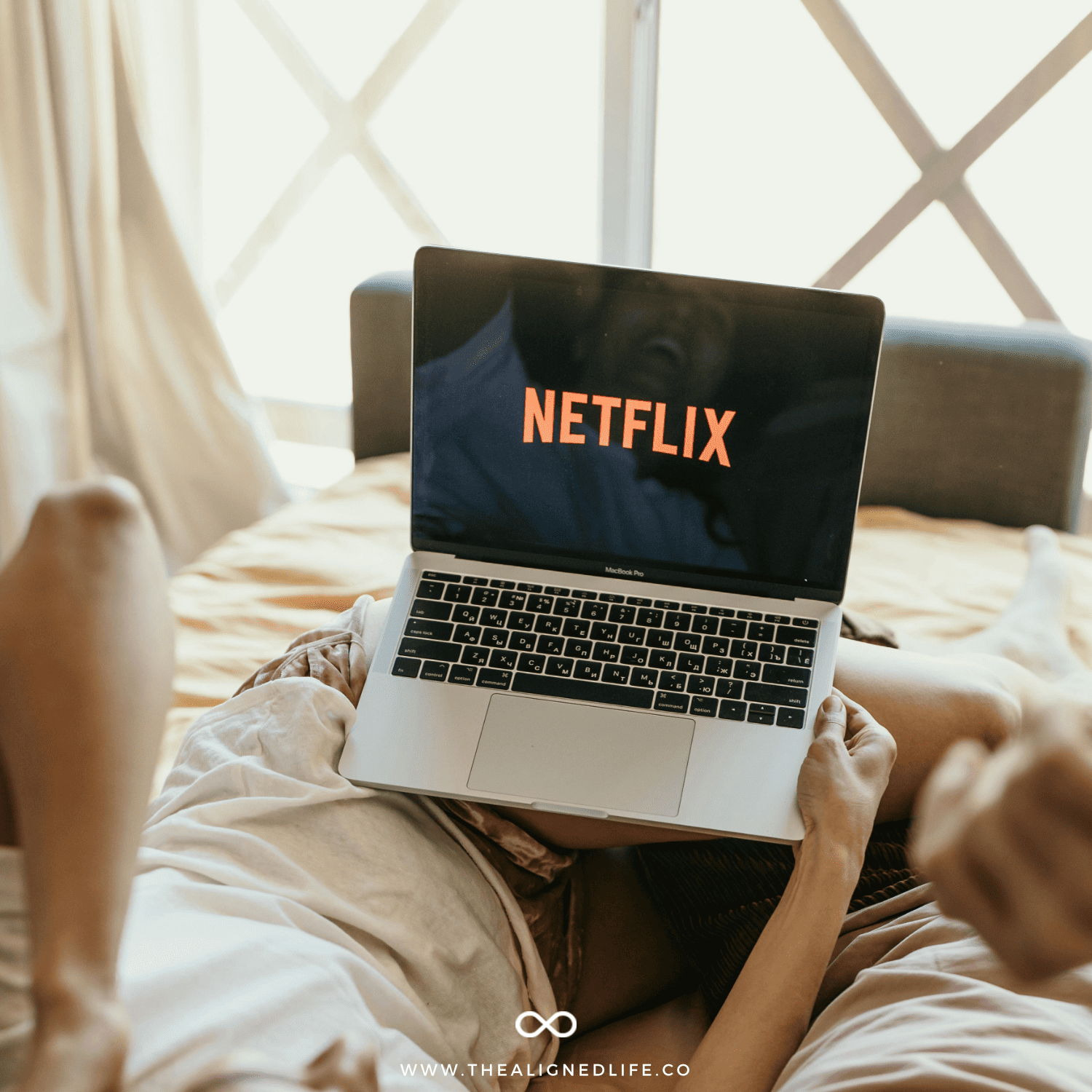 couple watching Netflix on a laptop in bed | Spiritual Shows To Watch On Netflix | The Aligned Life Manifestation Blog