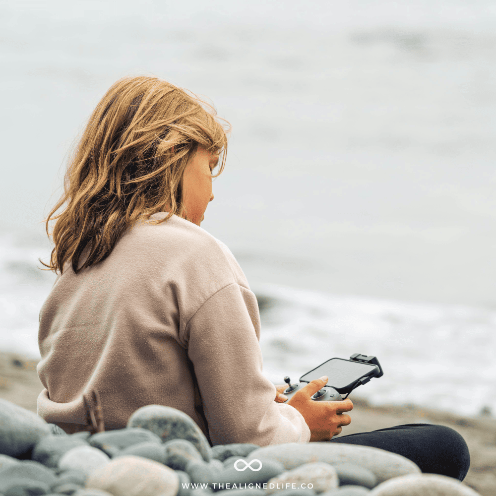 woman on the beach with her phone | Free Manifestation Wallpaper | Phone Backgrounds | The Aligned Life Manifestation Blog