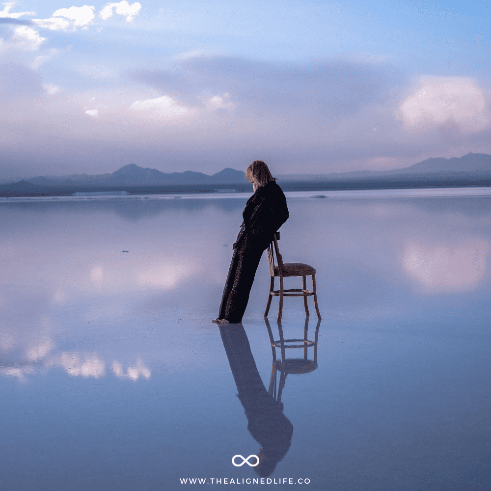 woman leaning on a chair in low water purple mountains reflection | How To Manifest | The Aligned Life Manifestation Blog