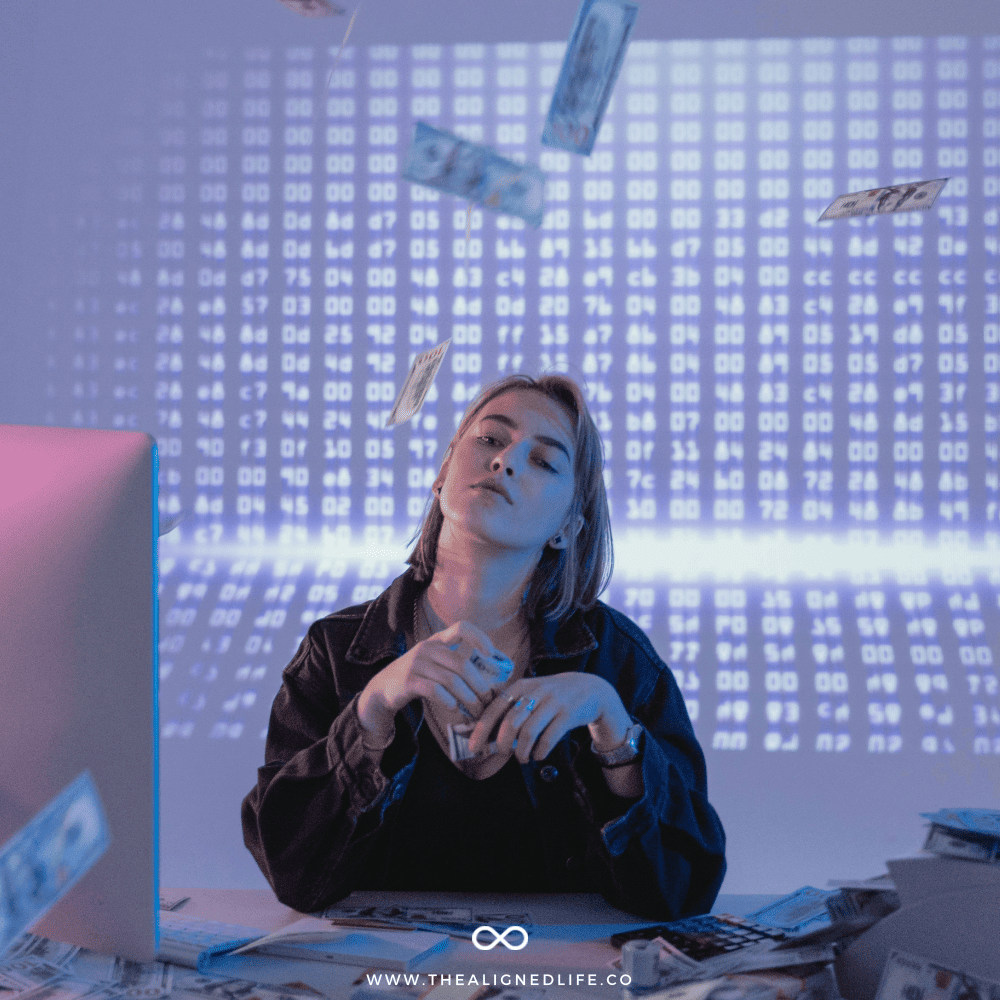 woman sitting a desk throwing money in the air | How To Manifest Money | The Aligned Life Manifestation Blog