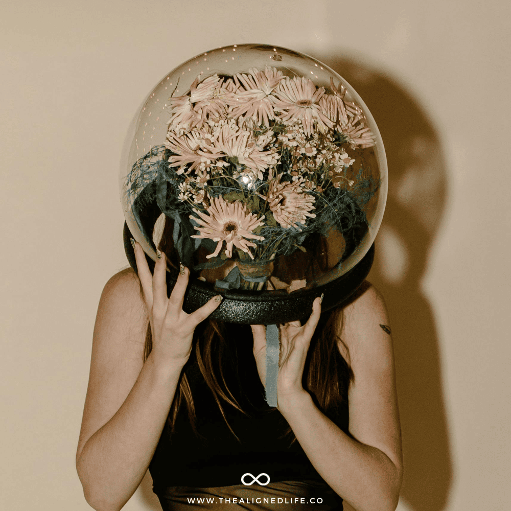 girl holding a giant globe with flowers in it | How To Manifest With Your Moon Sign | The Aligned Life Manifestation Blog