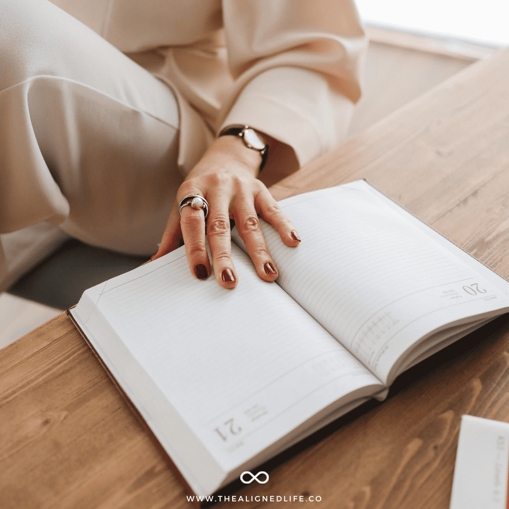 woman with her hand on a planner | Your Money Manifestation Plan | The Aligned Life Manifestation Blog