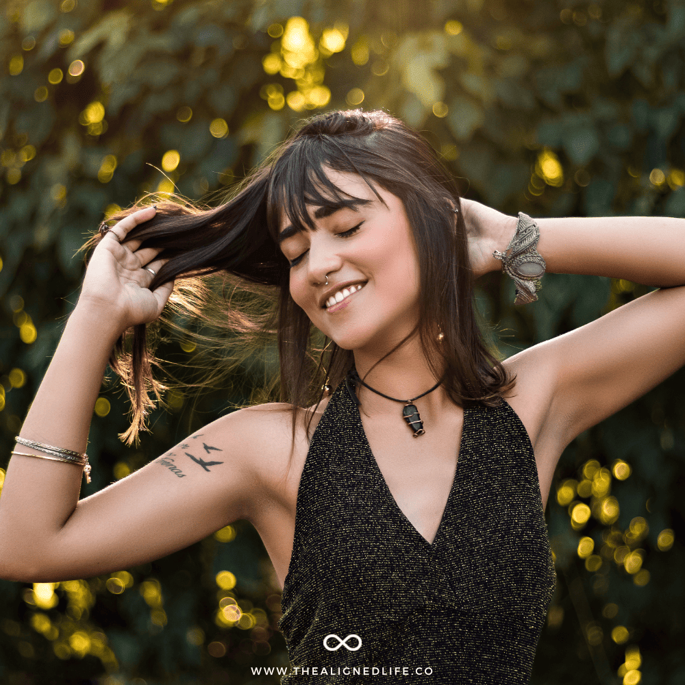 girl with her eyes closed playing with her hair | Most Common Money Manifestation Blocks (& How To Banish Them!) | The Aligned Life Manifestation Blog