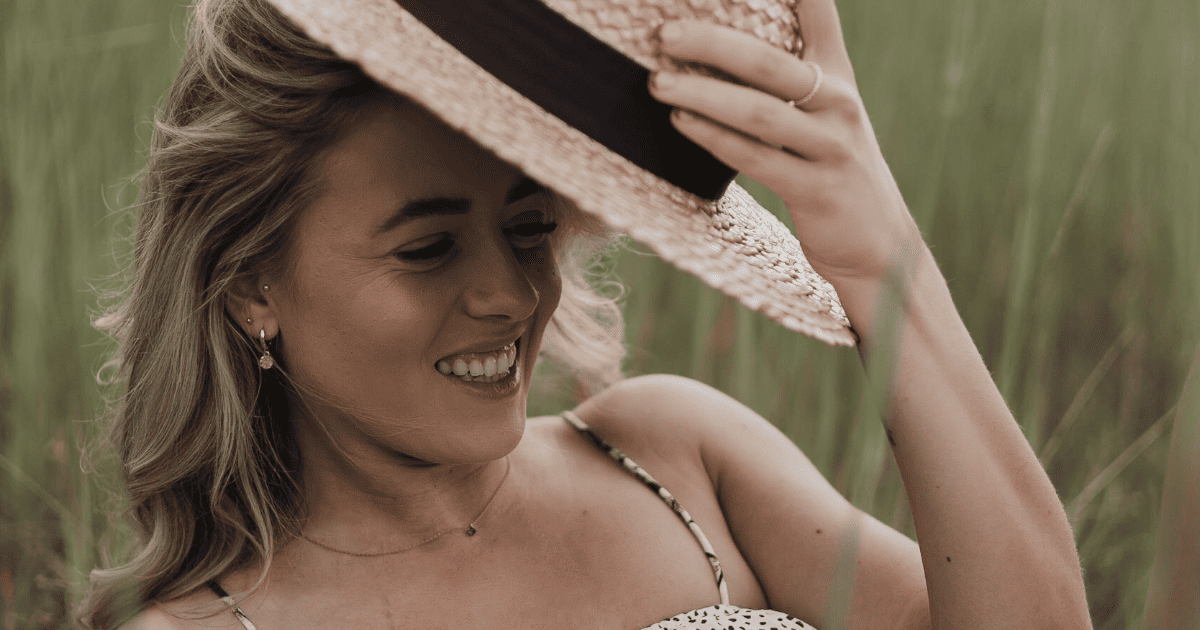 woman in a hat in the grass | 100 Powerful Manifestation Affirmations | The Aligned Life Manifestation Blog