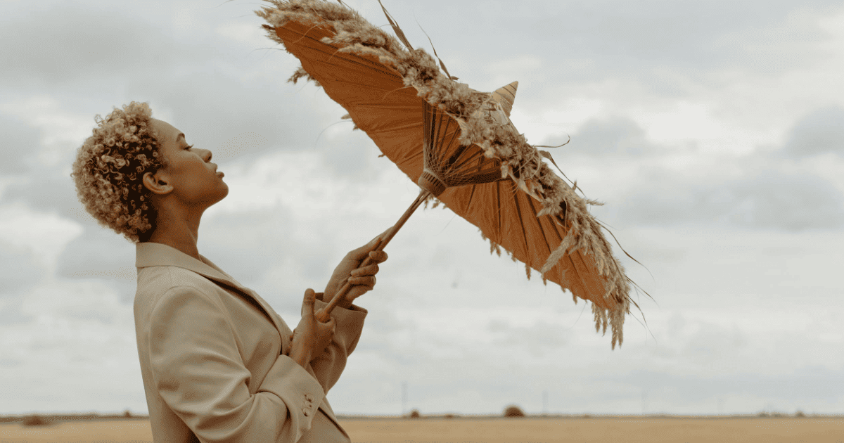 woman in a wheat field with an umbrella | Splenic Authority In Human Design Explained