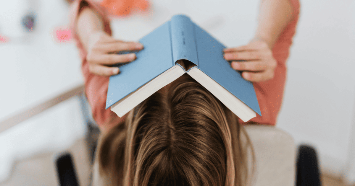 blonde woman studying with book over her face