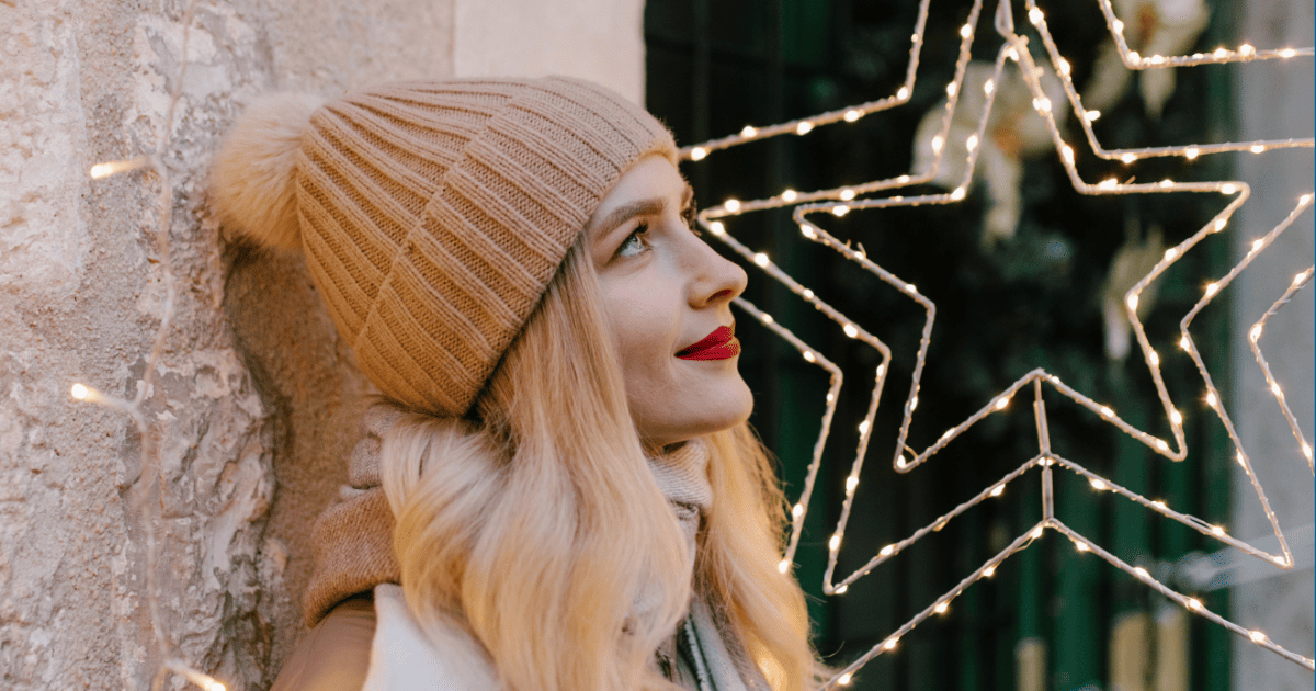blonde woman in a beanie stands next to a star ornament | The Spiritual Holiday Survival Guide: Stay Chill Not Triggered