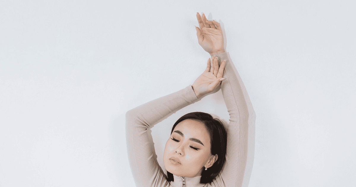 asian woman with her eyes closed against a white wall | Free Human Design Calculator
