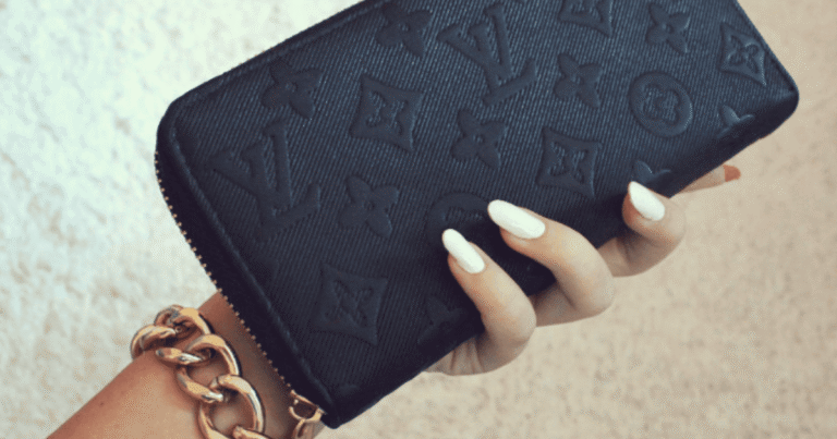 woman's hand with white manicure holding a black Louis Vuitton wallet | 10 Feng Shui Tricks for Money & Abundance